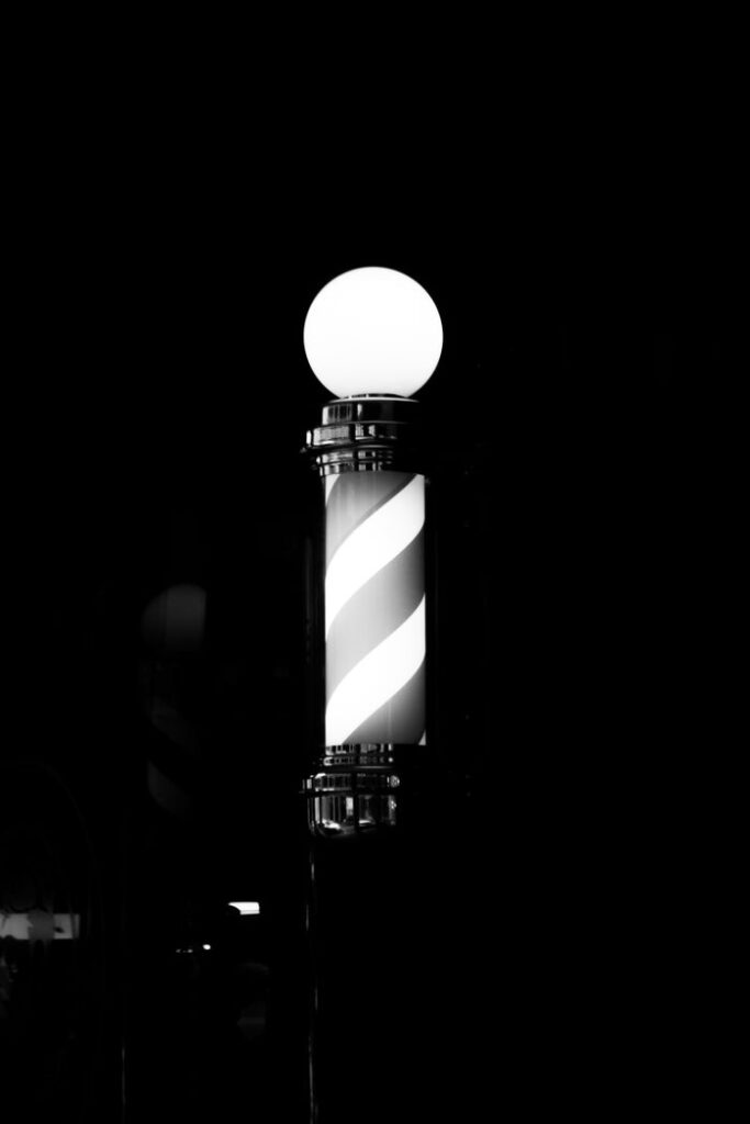 A classic black and white barber pole glowing against the night sky.